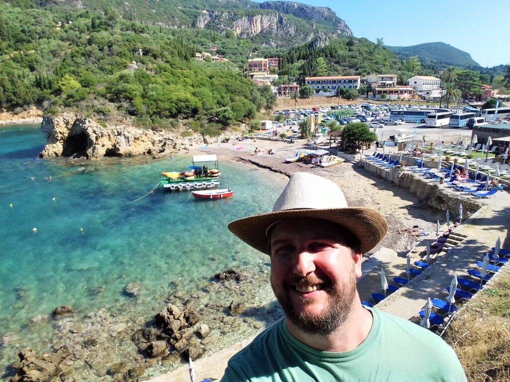 Glifada – duga peščana plaža na zapadu Krfa, sunce koje tone u Jonsko more, blagi vetar nosi mirise borova