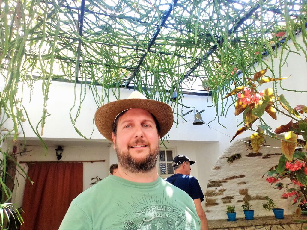 Autor istražuje manastir na Krfu, sa zvonikom u pozadini i panoramskim pogledom na more i stene.