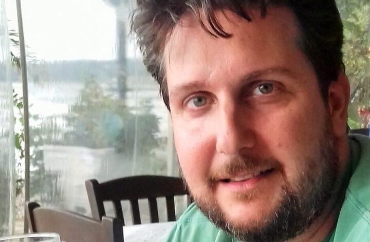 Autor bloga za stolom, uživajući u čaši krfskog vina 🍷, sa pogledom na mediteranski pejzaž.